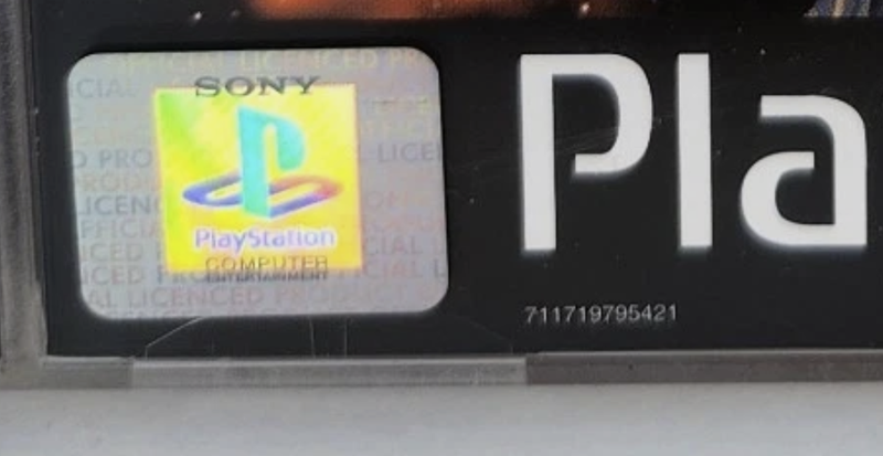 An unedited photo of a genuine PlayStation hologram showing the Official Licensed Product background text, SONY above the logo and Computer Entertainment beneath it.