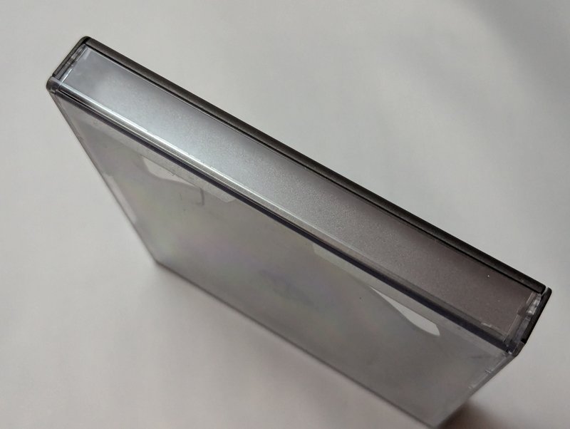 Opposite side profile of the mini jewel case showing the hinge spine and the hybrid clear and black plastic construction.