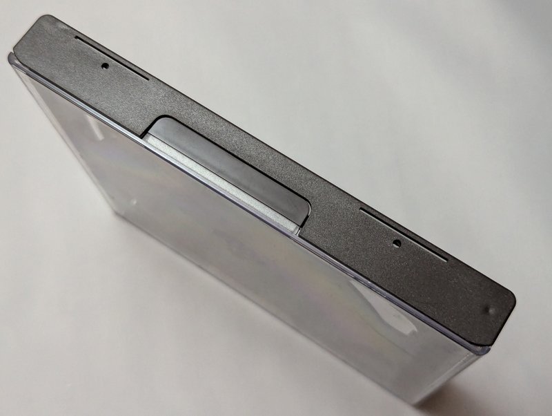 Top edge of the mini jewel case showing the black plastic latch mechanism and the thick black plastic construction.