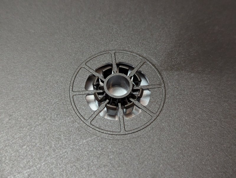 Close-up of the black tray spindle hub showing the six retaining clips that grip the disc centre hole.