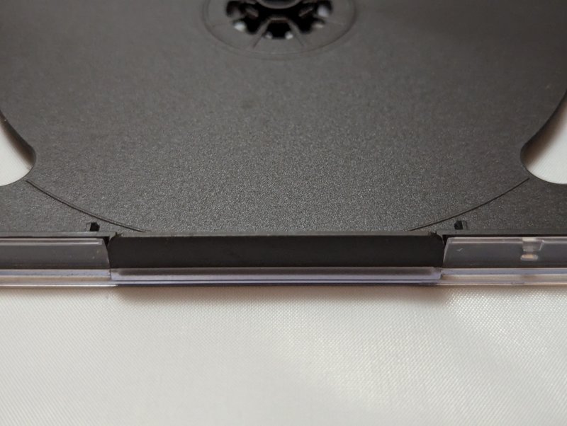 Close-up of the bottom edge of the black tray showing the retention clip mechanism where the tray locks into the case.